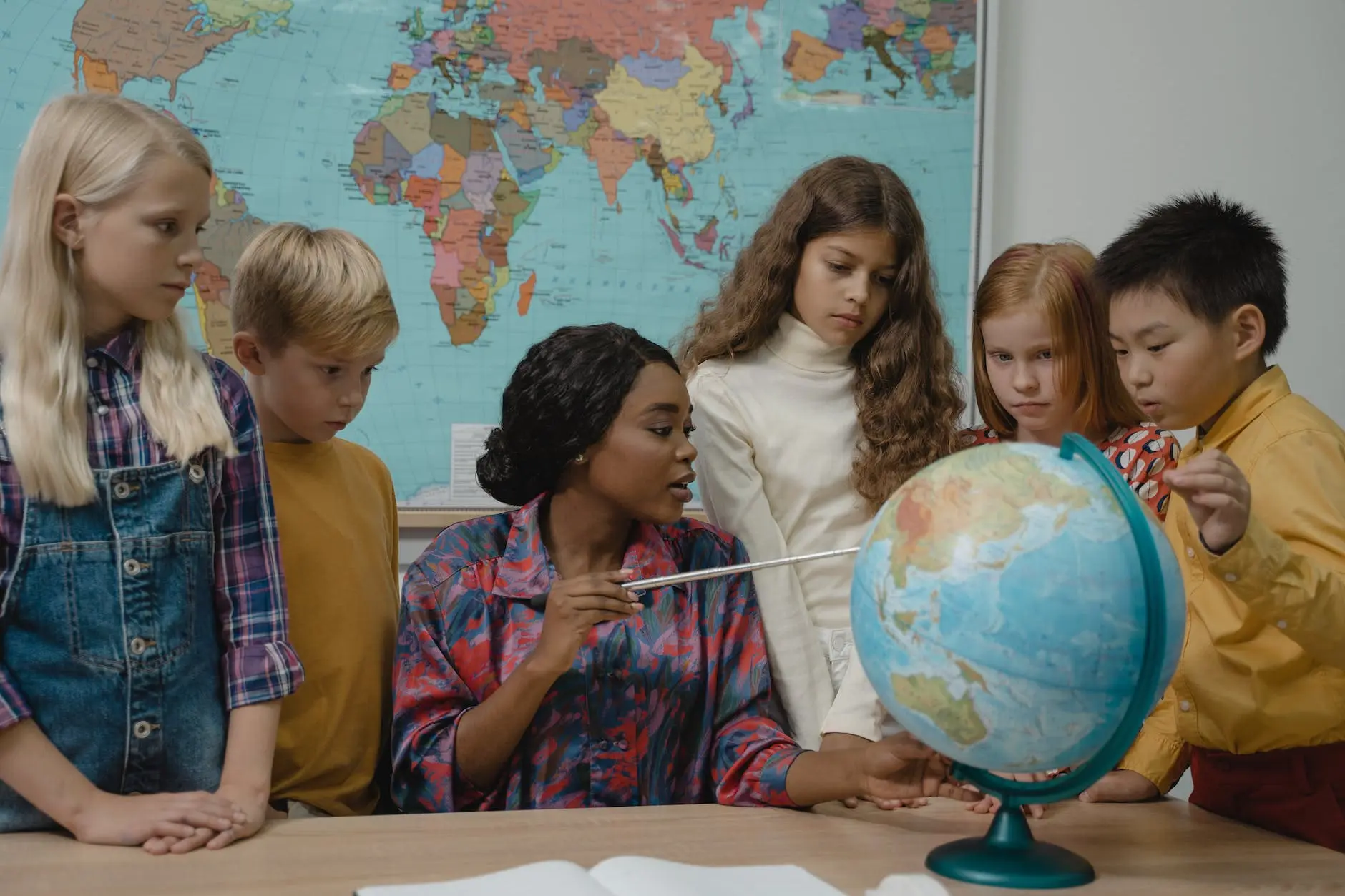 teacher teaching students about geography using a globe