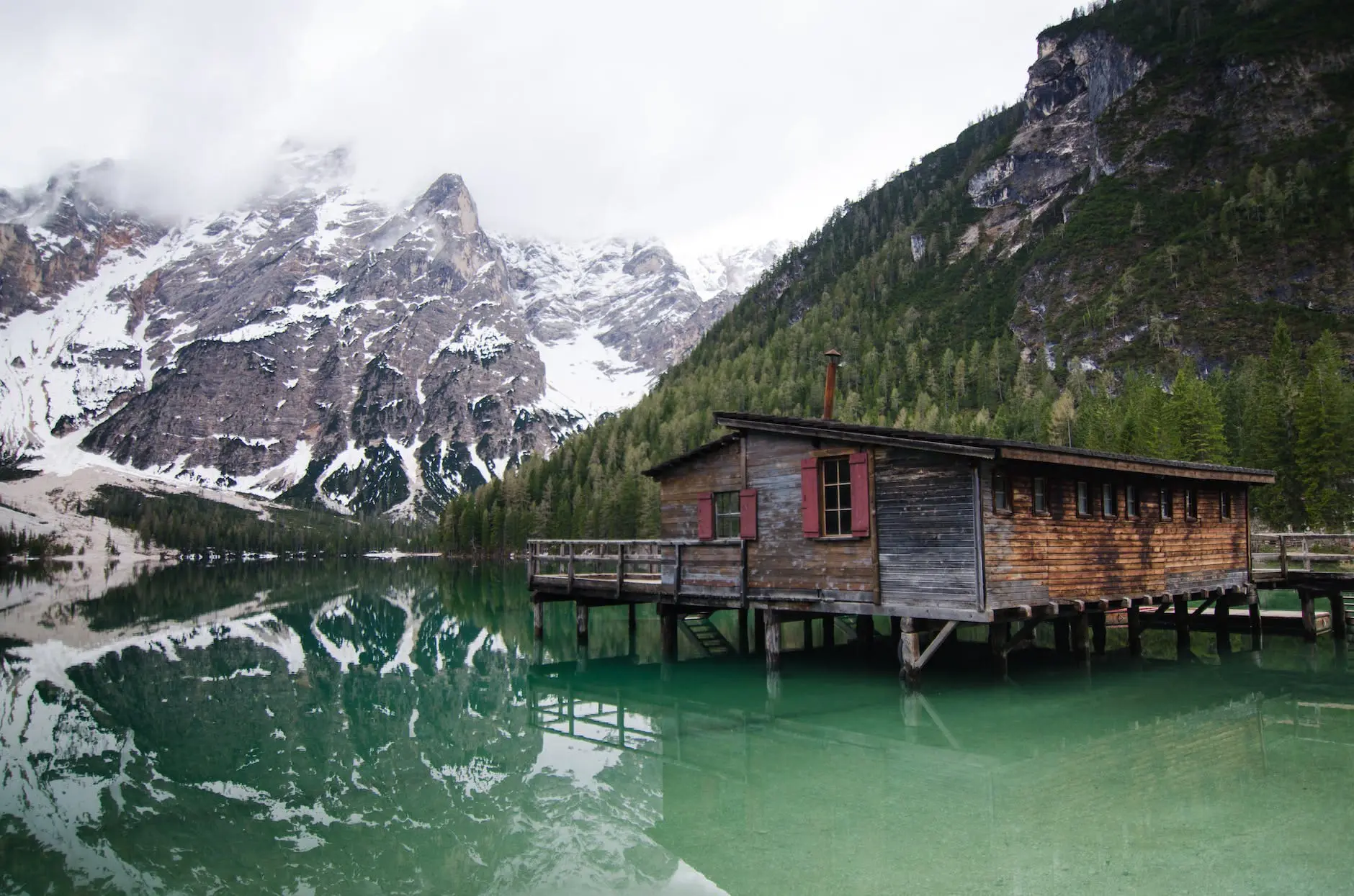 brown wooden house o lake near snow covered mountain
