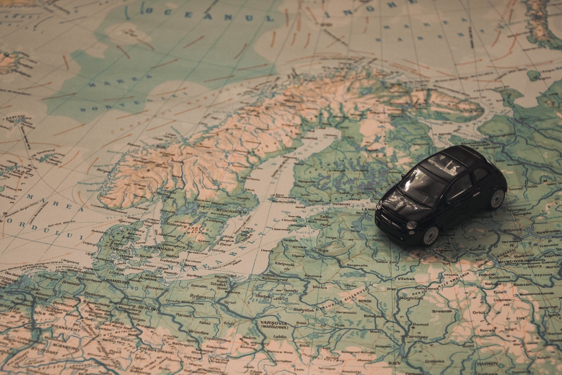 black toy car on world map paper - Oslo Norway Rental Car Guide