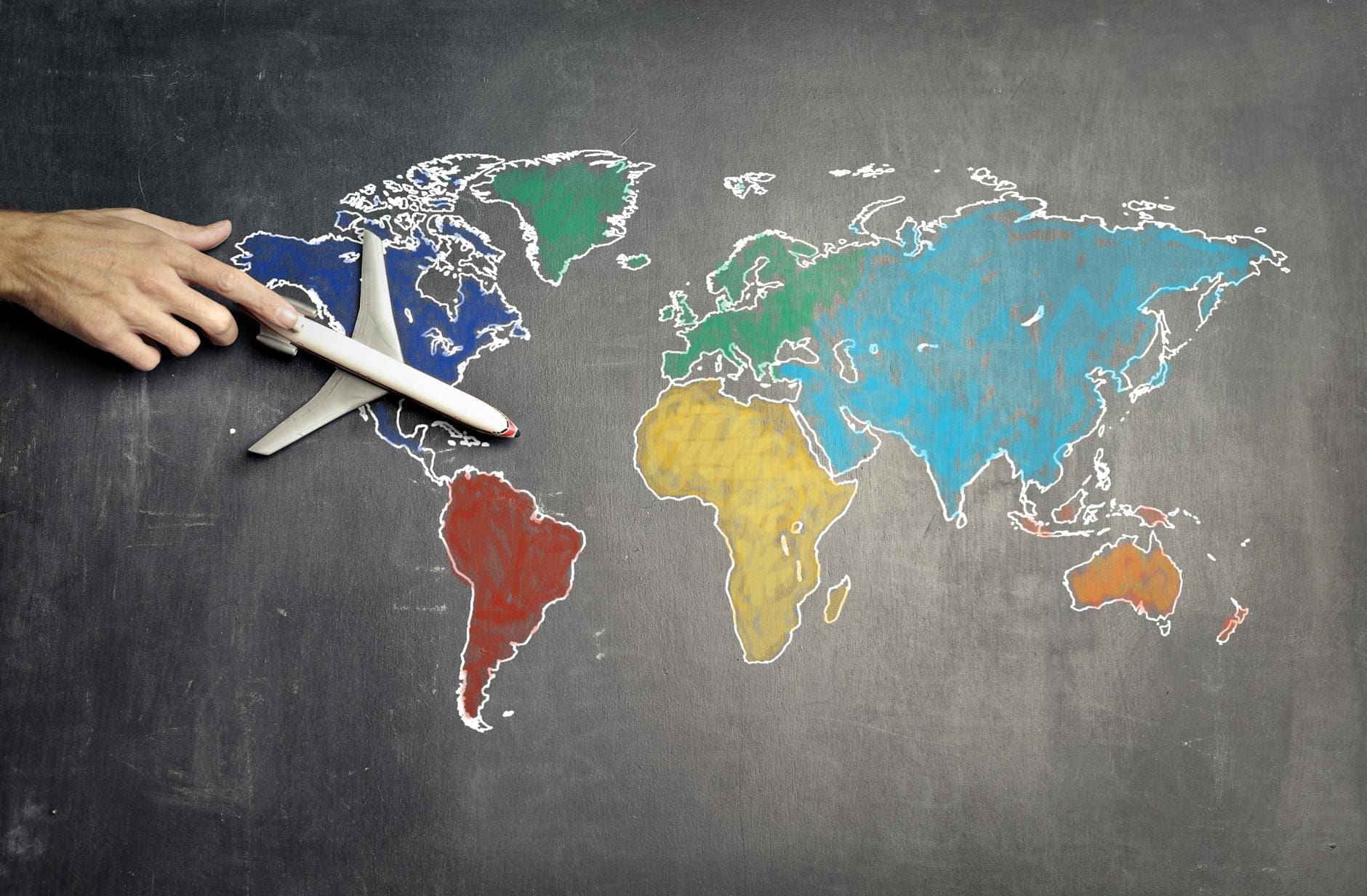 person with toy airplane on world map to set goals examples