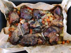 Lamb bones and vegetables in a baking tray ready for slowly roasting
